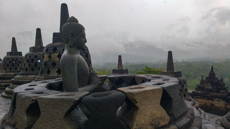 Buda visto desde lateral de una campana abierta del templo de borobudur
