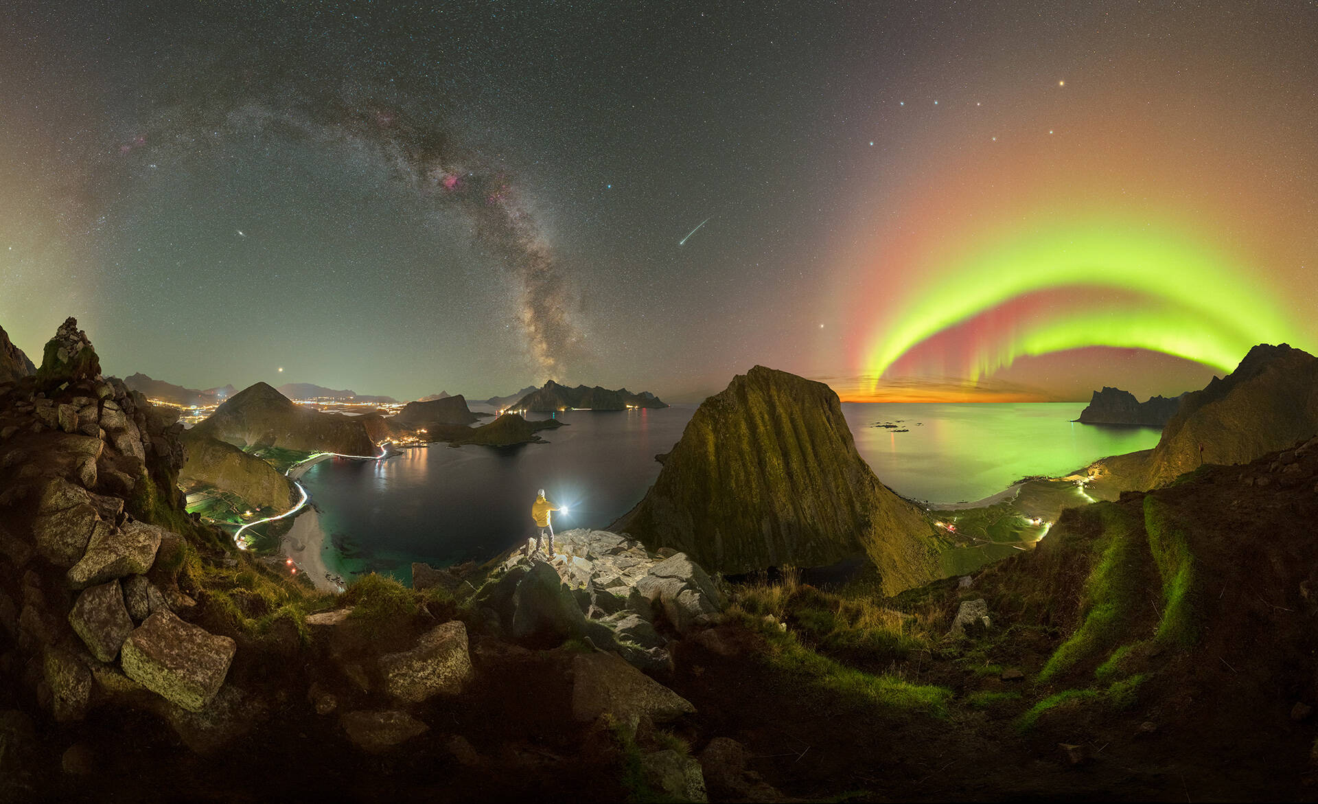 Panorámica de un arco de la Vía Láctea junto a un arco de Aurora Boreal cubren el cielo nocturno