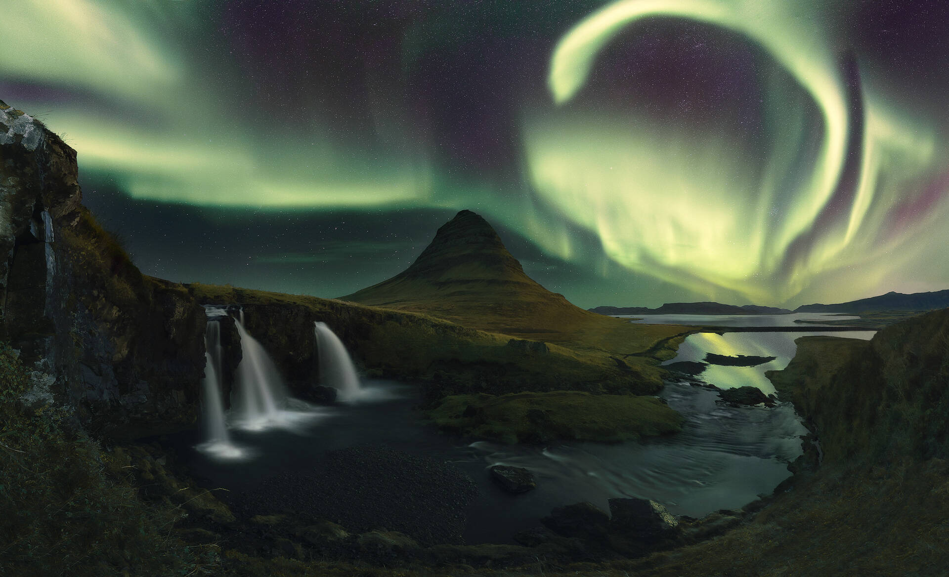 Panorámica de una Aurora Borel cubriendo el cielo sobre Kirkjufell en Islandia