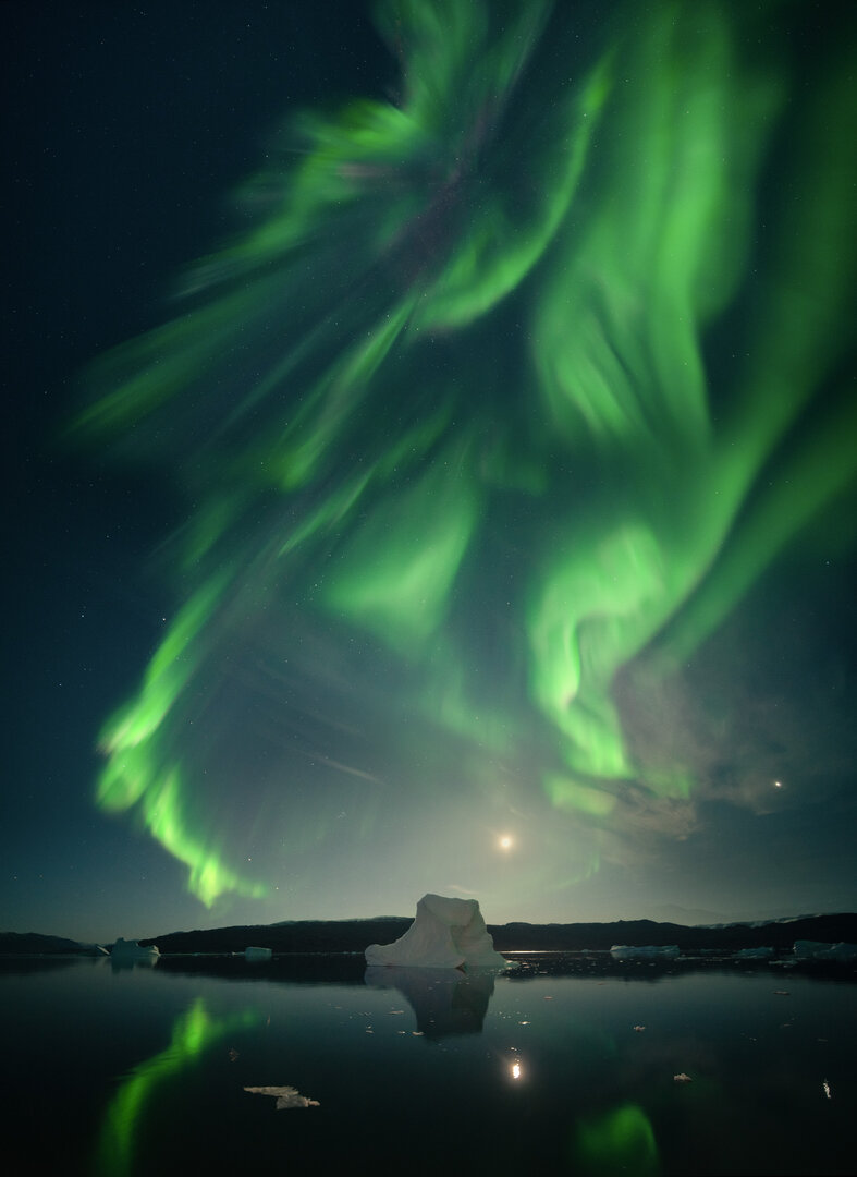 Aurora Boreal cubre el cielo nocturno sobre un mar helado con icebergs