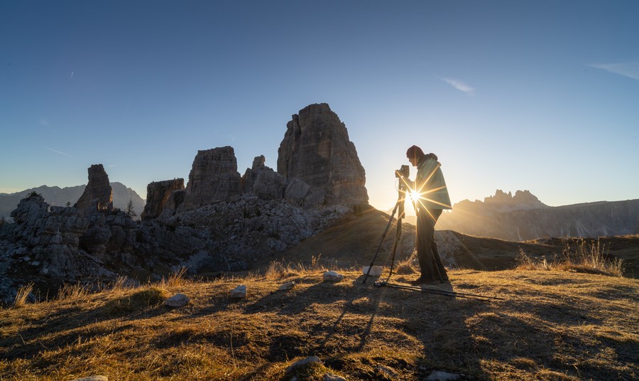 Person taking a photograph of Cinque Torri during sunrise