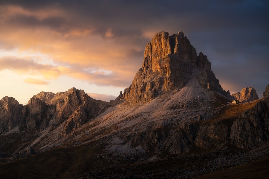 Dramatic sunset in Passo Giau with thich clouds painted by the golden light of the sun setting