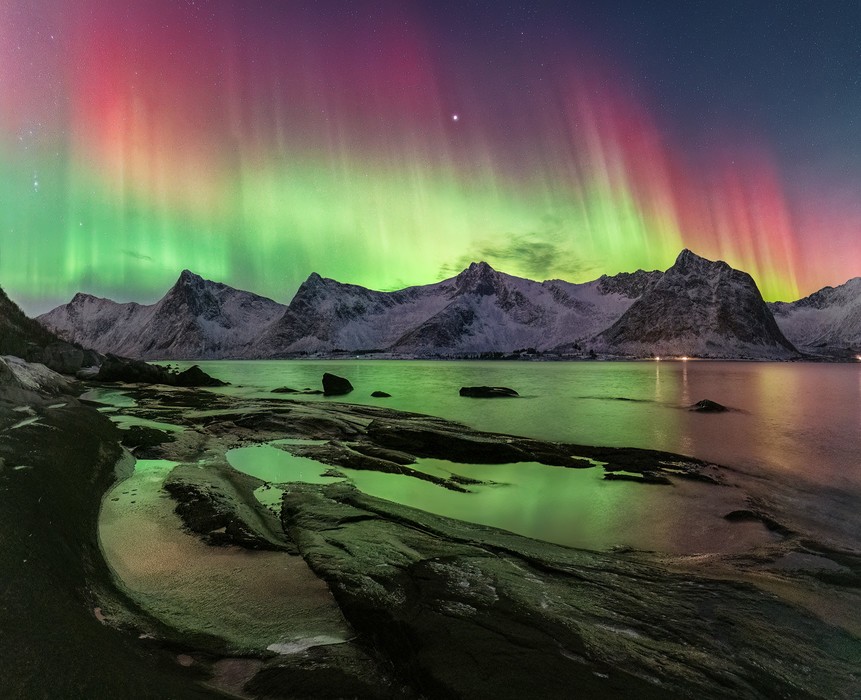 Include foreground elements in your Northern Lights photos Bright red and greed northern lights over some snow-caped mountains in Norway