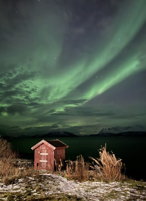 Northern Lights photographed with a iPhone Green Northern Lights covering the sky over a small red cabin