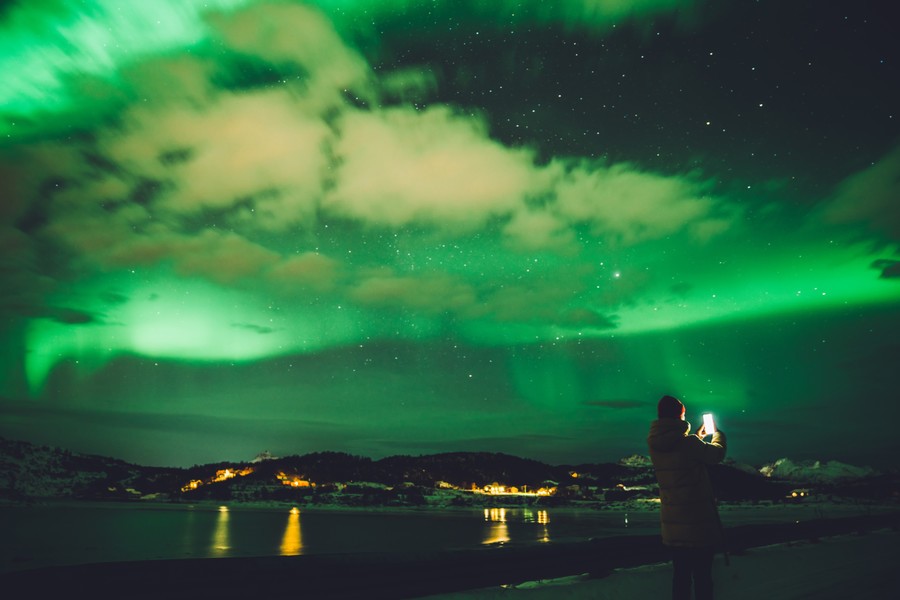 Use your smartphone to photograph northern lights person photographing the northern lights with a smartphone