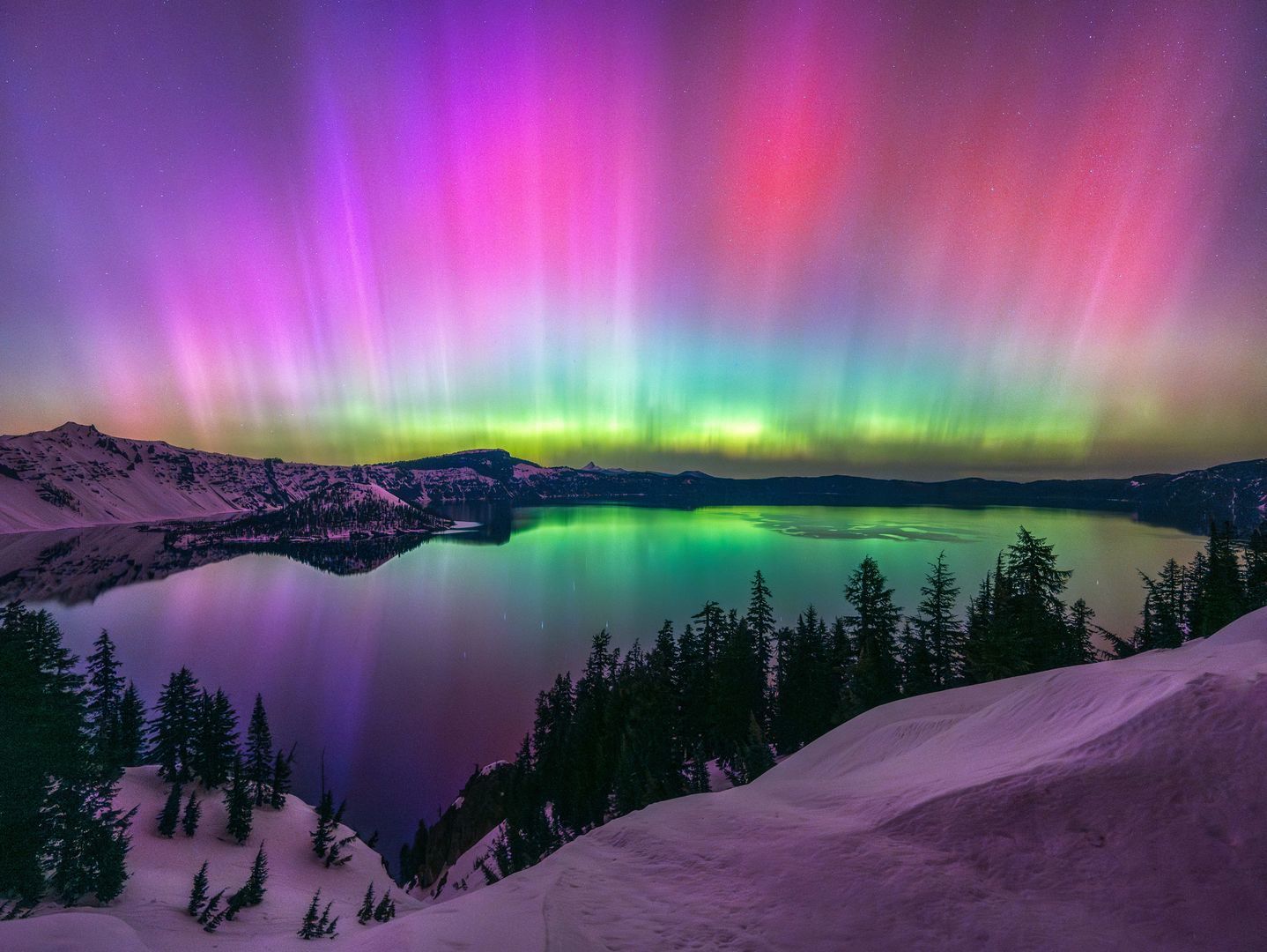 Northern Lights over Crater Lake Bright red and green northern lights shine and reflect over a lake